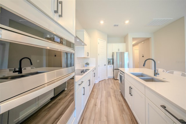 16055 Silver Brook Way, Winter Garden, FL 34787 - kitchen featuring a sink, appliances with stainless steel finishes, light wood-type flooring, white cabinets, and light countertops