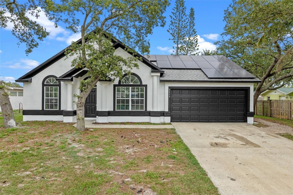 6635 Miraflores Ave, Cocoa, FL 32927 - view of front facade with a garage, solar panels, driveway, stucco siding, and roof with shingles