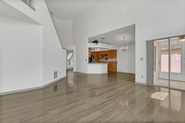 485 Whittingham Pl, Lake Mary, FL 32746 - unfurnished living room featuring a towering ceiling, light wood-style flooring, a chandelier, and a ceiling fan
