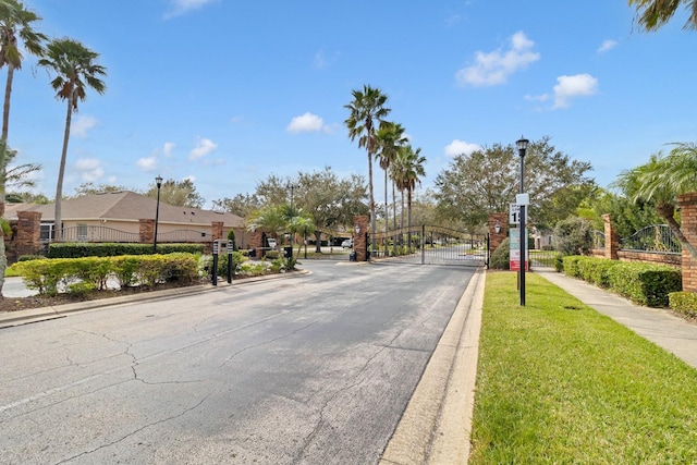 1913 Lazy Oaks Loop, Saint Cloud, FL 34771 - view of asphalt street with a gate, street lights, sidewalks, curbs, and a gated entry