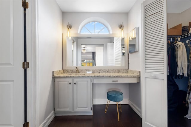 1616 Golden Poppy Ct, Orlando, FL 32824 - bathroom featuring vanity, wood finished floors, baseboards, a walk in closet, and a ceiling fan