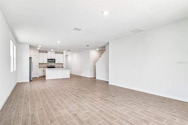 1740 Brekey Way, Zephyrhills, FL 33541 - unfurnished living room featuring light wood finished floors and recessed lighting