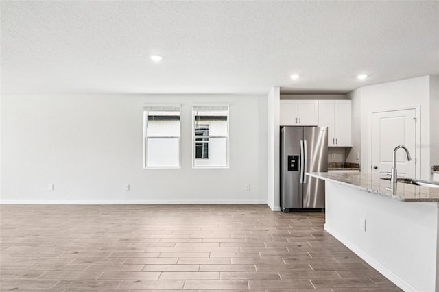 1740 Brekey Way, Zephyrhills, FL 33541 - kitchen featuring stainless steel fridge, wood finished floors, light stone counters, recessed lighting, and a textured ceiling
