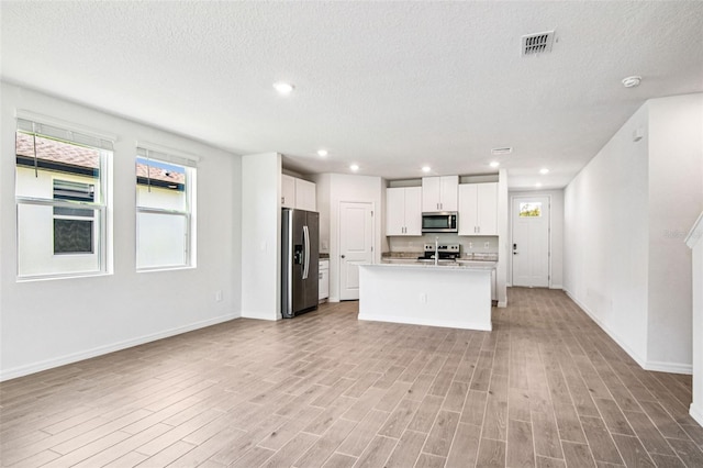 1740 Brekey Way, Zephyrhills, FL 33541 - kitchen with stainless steel appliances, white cabinets, light wood-type flooring, light countertops, and open floor plan