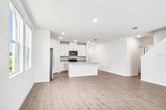 1740 Brekey Way, Zephyrhills, FL 33541 - kitchen featuring appliances with stainless steel finishes, open floor plan, light wood-type flooring, light countertops, and white cabinetry