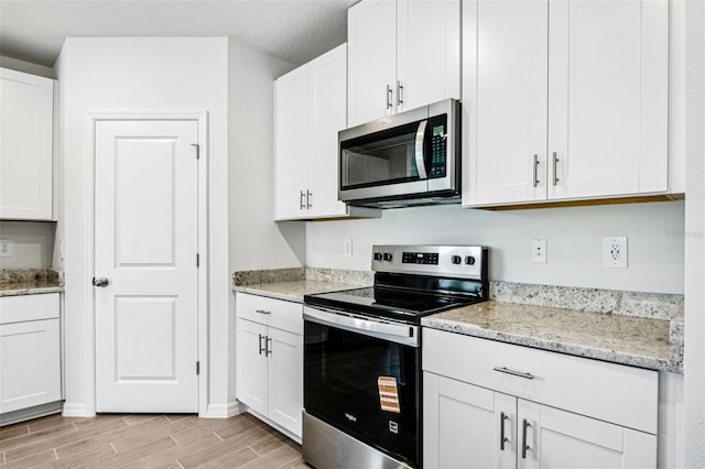 1740 Brekey Way, Zephyrhills, FL 33541 - kitchen featuring stainless steel appliances, wood tiled floors, white cabinetry, and light stone countertops