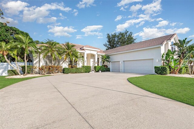 6121 Oxbow Bend Ln, Port Orange, FL 32128 - mediterranean / spanish-style house featuring concrete driveway, an attached garage, stucco siding, a tile roof, and a front yard