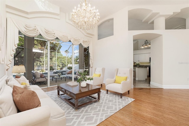6121 Oxbow Bend Ln, Port Orange, FL 32128 - living room featuring arched walkways, light wood-type flooring, a chandelier, baseboards, and a high ceiling