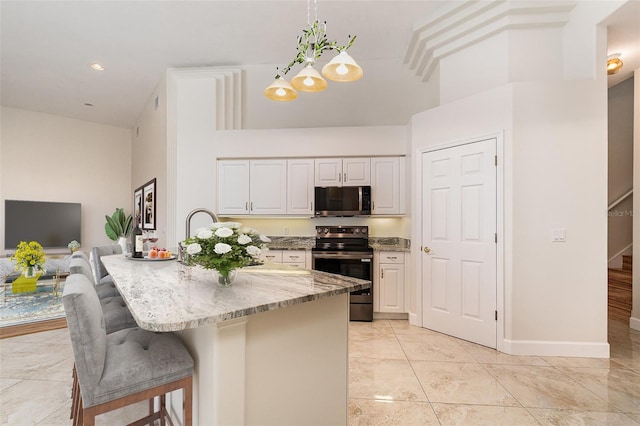 6121 Oxbow Bend Ln, Port Orange, FL 32128 - kitchen featuring appliances with stainless steel finishes, light stone countertops, a towering ceiling, white cabinets, and a breakfast bar