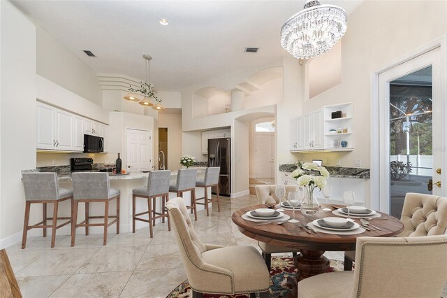 6121 Oxbow Bend Ln, Port Orange, FL 32128 - dining area featuring light marble finish flooring, a chandelier, a towering ceiling, baseboards, and arched walkways