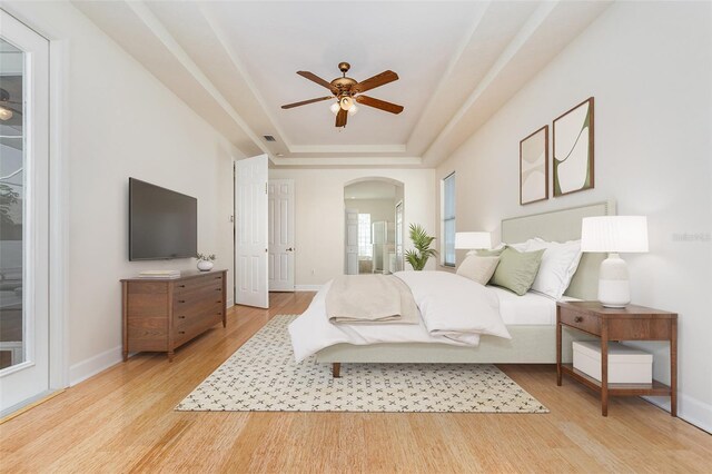 6121 Oxbow Bend Ln, Port Orange, FL 32128 - bedroom featuring a tray ceiling, light wood finished floors, arched walkways, and baseboards