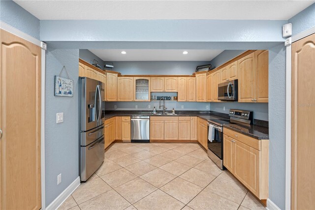 2110 W Farwell Dr, Tampa, FL 33603 - kitchen with appliances with stainless steel finishes, light brown cabinetry, dark countertops, a sink, and light tile patterned floors