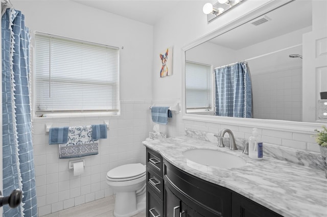 217 Spencer St, Orlando, FL 32839 - full bathroom featuring tile walls, vanity, toilet, curtained shower, and wainscoting