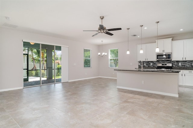 7308 Hermes Ct, Apollo Beach, FL 33572 - kitchen featuring stainless steel appliances, dark countertops, ceiling fan, tasteful backsplash, and open floor plan