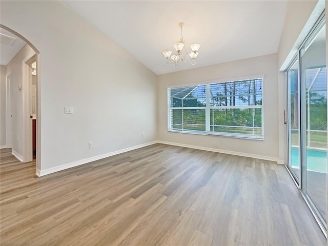 13210 Essman Ave, Port Charlotte, FL 33953 - spare room with vaulted ceiling, arched walkways, a chandelier, wood finished floors, and baseboards