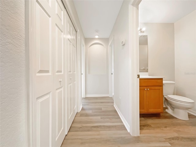 13210 Essman Ave, Port Charlotte, FL 33953 - hallway featuring light wood-style flooring, a textured wall, and baseboards