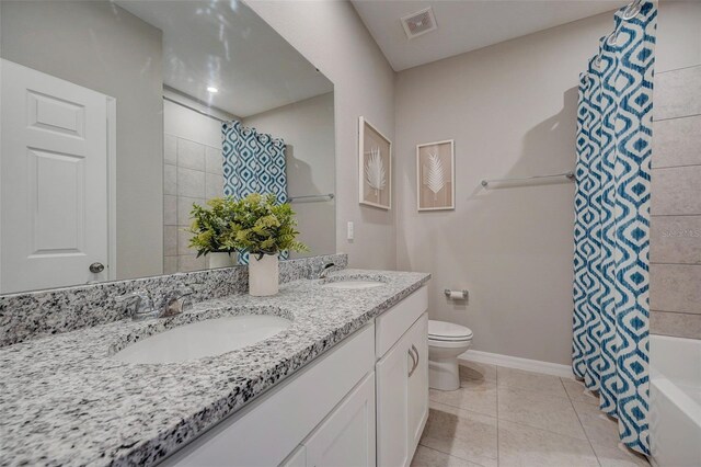 1323 Normandy Dr, Haines City, FL 33844 - full bathroom featuring double vanity, toilet, baseboards, shower / bath combo with shower curtain, and tile patterned flooring