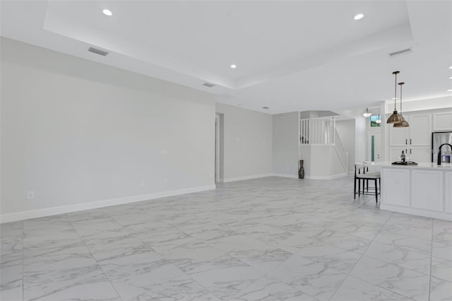 32740 Tree Of Life Ave, Wesley Chapel, FL 33543 - unfurnished living room with a raised ceiling, baseboards, recessed lighting, stairs, and light marble finish floors