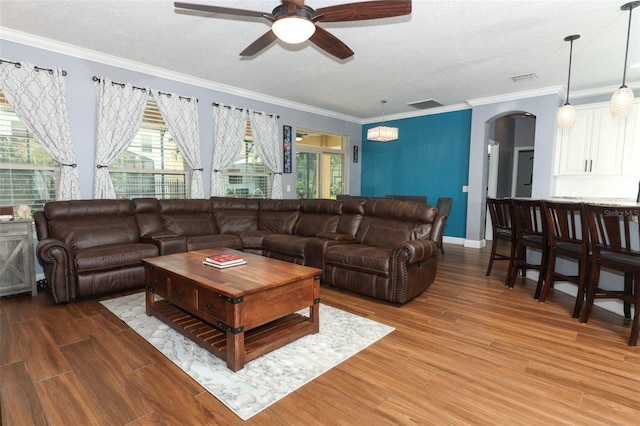 319 Morning View Dr, Winter Garden, FL 34787 - living room featuring arched walkways, ceiling fan, light wood finished floors, crown molding, and a textured ceiling