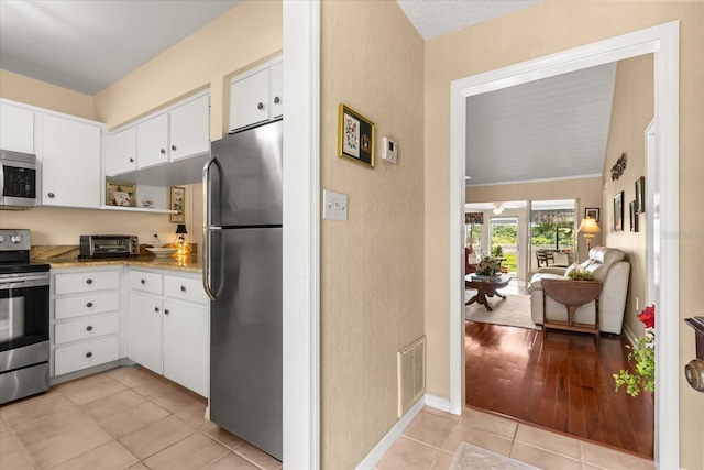 1146 Villa Ln Unit 101, Apopka, FL 32712 - kitchen featuring appliances with stainless steel finishes, light tile patterned floors, white cabinetry, and baseboards