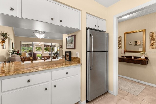 1146 Villa Ln Unit 101, Apopka, FL 32712 - kitchen with freestanding refrigerator, white cabinets, light tile patterned flooring, light stone counters, and baseboards