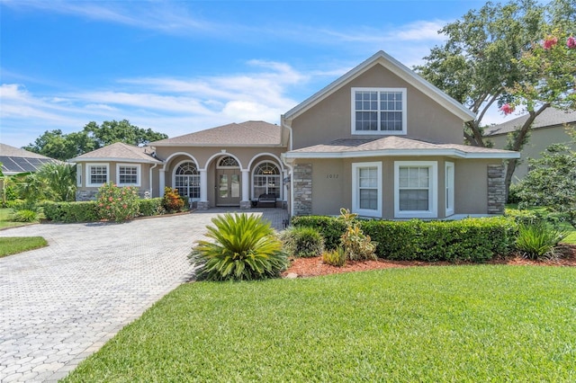 1017 Parkside Pointe Blvd, Apopka, FL 32712 - view of front of home with stucco siding, stone siding, a front lawn, decorative driveway, and french doors