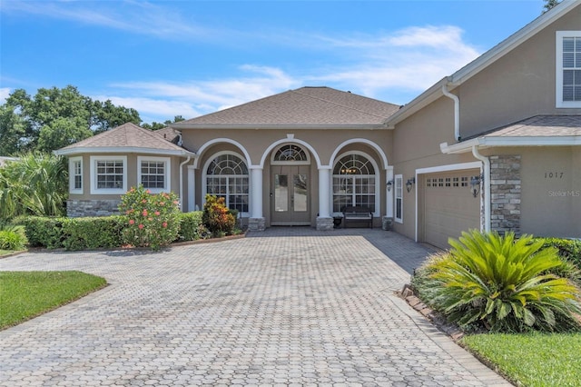 1017 Parkside Pointe Blvd, Apopka, FL 32712 - view of front of house featuring stone siding, decorative driveway, stucco siding, a garage, and french doors