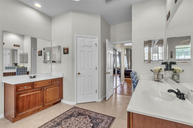 1017 Parkside Pointe Blvd, Apopka, FL 32712 - bathroom featuring two vanities, tile patterned flooring, a towering ceiling, and baseboards