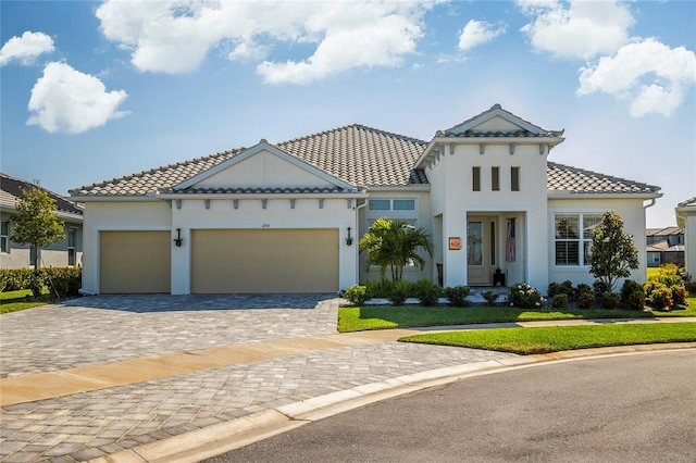 4754 Manning Ct, Sarasota, FL 34240 - mediterranean / spanish-style house with decorative driveway, stucco siding, an attached garage, a tiled roof, and a front lawn