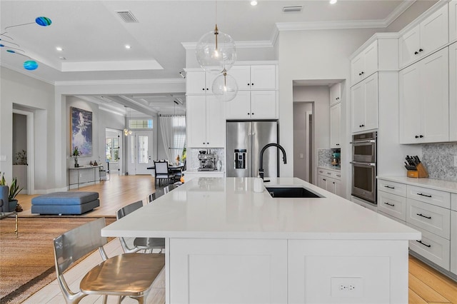 4754 Manning Ct, Sarasota, FL 34240 - kitchen featuring appliances with stainless steel finishes, a sink, light countertops, light wood-type flooring, and crown molding