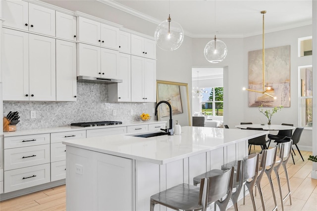 4754 Manning Ct, Sarasota, FL 34240 - kitchen with a sink, decorative backsplash, a breakfast bar, crown molding, and white cabinetry