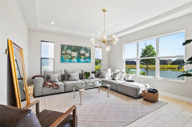 4754 Manning Ct, Sarasota, FL 34240 - living area featuring a chandelier, a tray ceiling, a water view, baseboards, and wood finished floors