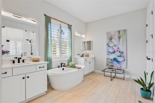 4754 Manning Ct, Sarasota, FL 34240 - full bathroom with two vanities, a soaking tub, wood finished floors, a stall shower, and baseboards