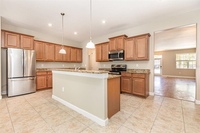 11621 Ashton Field Ave, Riverview, FL 33579 - kitchen with appliances with stainless steel finishes, light tile patterned floors, a kitchen island with sink, light stone counters, and brown cabinetry