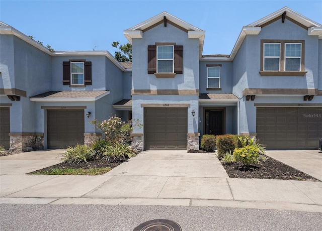6703 Citrus Creek Ln, Tampa, FL 33625 - townhome / multi-family property featuring a garage, stone siding, stucco siding, and driveway