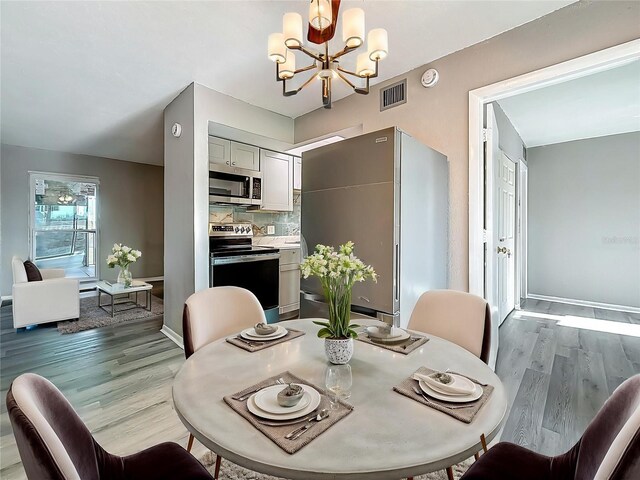 6100 12th St S Unit 313, Saint Petersburg, FL 33705 - dining space with wood finished floors, a chandelier, and baseboards