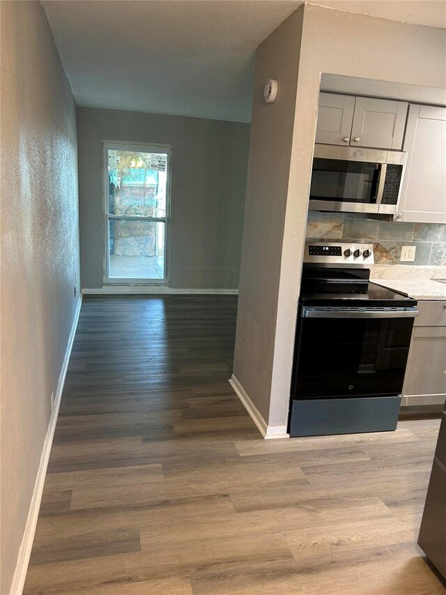 6100 12th St S Unit 313, Saint Petersburg, FL 33705 - kitchen featuring stainless steel appliances, light wood-style floors, tasteful backsplash, and baseboards