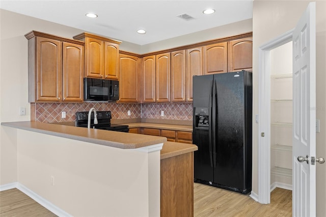 1062 Wickerwood St, Ocoee, FL 34761 - kitchen featuring black appliances, light wood-style flooring, a peninsula, backsplash, and recessed lighting