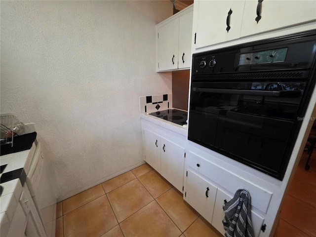 663 68th Ave S, Saint Petersburg, FL 33705 - kitchen with black appliances, white cabinets, and light tile patterned flooring