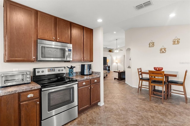 1805 Kingsmill Dr, Bartow, FL 33830 - kitchen with stainless steel appliances, arched walkways, dark countertops, brown cabinets, and vaulted ceiling