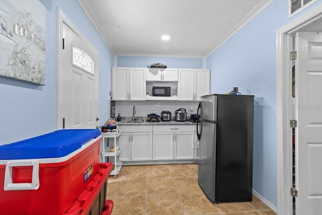 14506 Sutter Pl, Tampa, FL 33625 - kitchen with freestanding refrigerator, a sink, white cabinets, a textured ceiling, and decorative backsplash