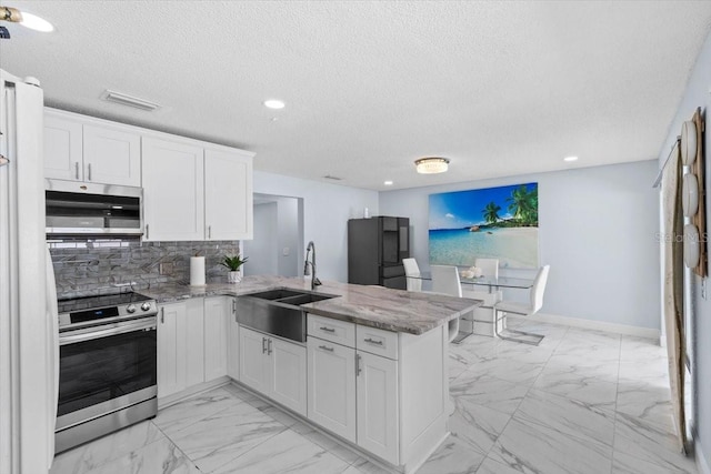 14506 Sutter Pl, Tampa, FL 33625 - kitchen with appliances with stainless steel finishes, a sink, a peninsula, light marble finish floors, and a textured ceiling