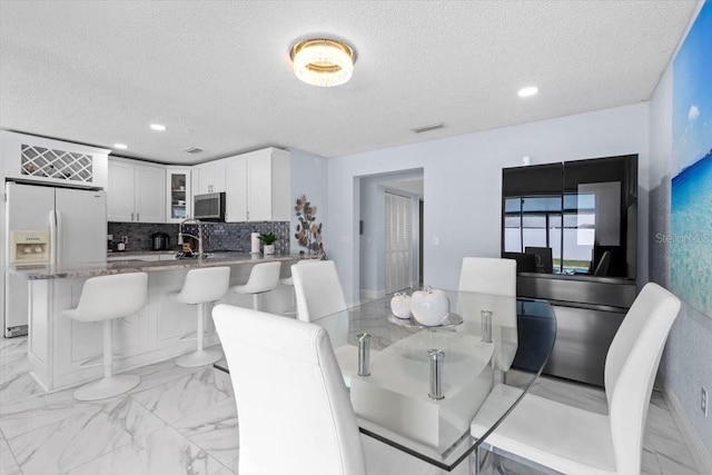 14506 Sutter Pl, Tampa, FL 33625 - dining area with a textured ceiling, light marble finish flooring, and recessed lighting