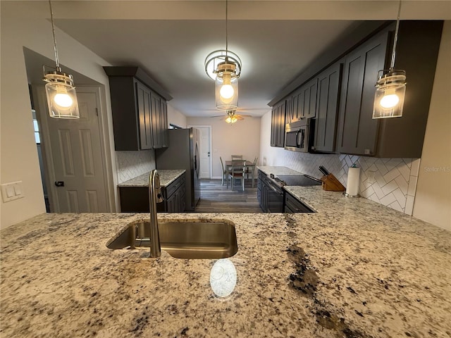 kitchen with appliances with stainless steel finishes, light stone counters, backsplash, and a ceiling fan