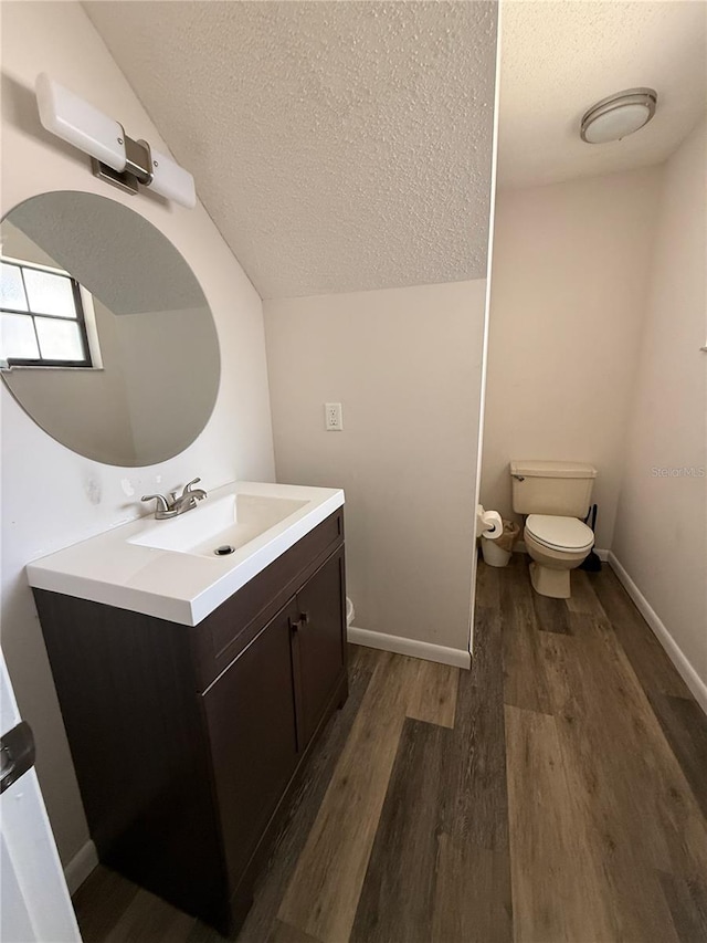bathroom with a textured ceiling, vanity, wood finished floors, and lofted ceiling