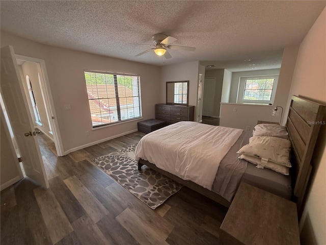 bedroom with dark wood-type flooring, multiple windows, a textured ceiling, and ceiling fan