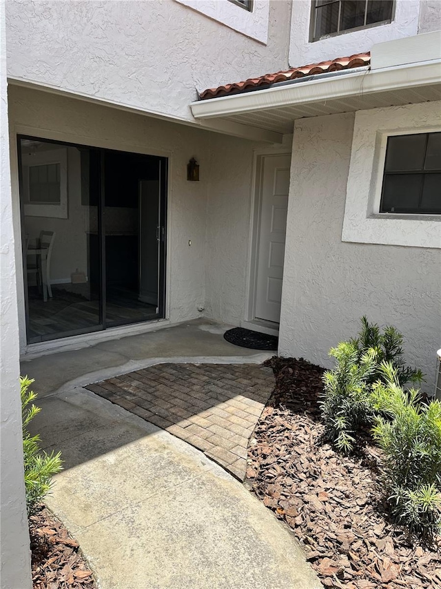 property entrance with stucco siding and a patio area