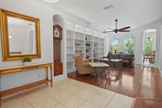 13631 Via Roma Cir, Clermont, FL 34711 - living area featuring ceiling fan, arched walkways, built in shelves, light wood-type flooring, and a textured ceiling