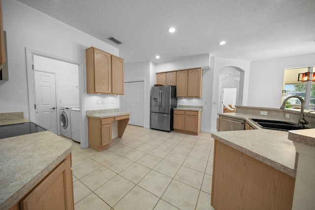 13631 Via Roma Cir, Clermont, FL 34711 - kitchen with stainless steel appliances, washing machine and dryer, arched walkways, light countertops, and a textured ceiling