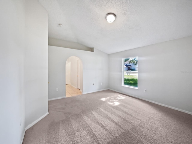 612 Doe Cove Pl, Apopka, FL 32703 - empty room with arched walkways, carpet floors, lofted ceiling, a textured ceiling, and baseboards
